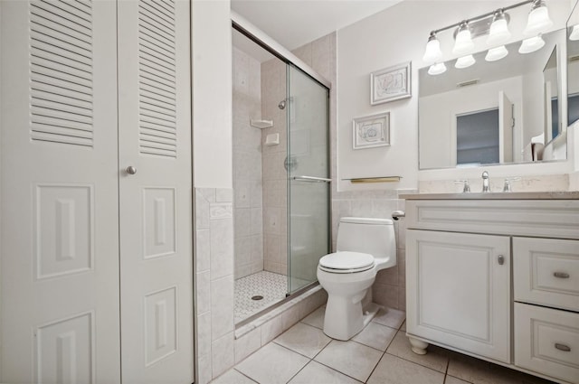 bathroom with a shower with door, vanity, toilet, and tile patterned floors