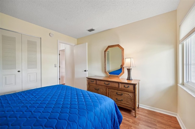 bedroom featuring a closet, a textured ceiling, multiple windows, and light hardwood / wood-style floors