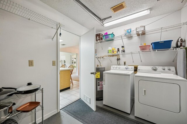 laundry room featuring water heater, washing machine and dryer, and a textured ceiling