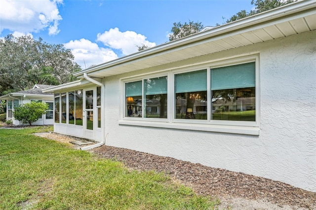 view of home's exterior featuring a sunroom and a lawn