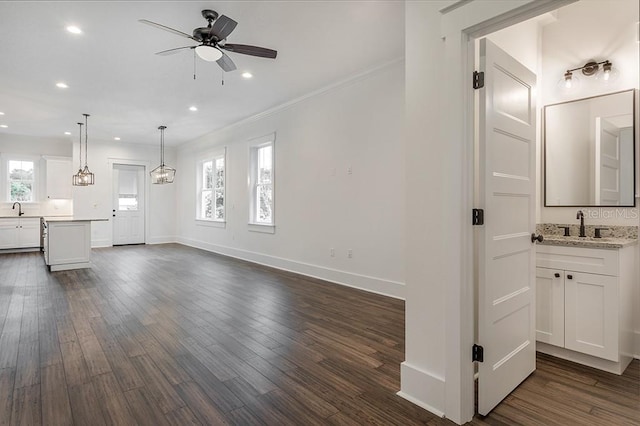 unfurnished living room featuring ornamental molding, dark hardwood / wood-style floors, ceiling fan, and sink