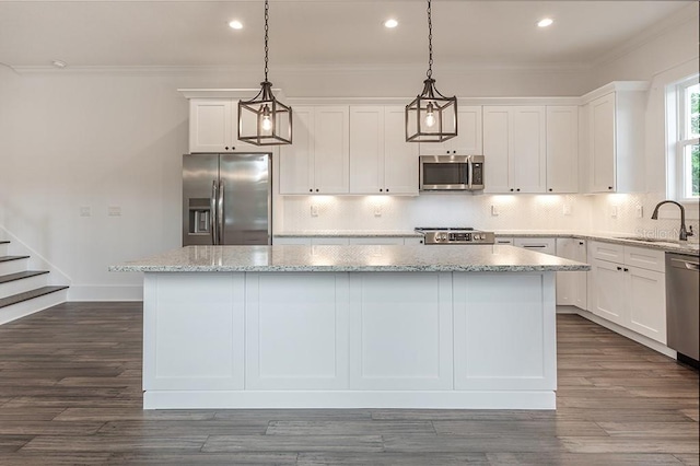 kitchen with decorative light fixtures, stainless steel appliances, white cabinets, and a center island