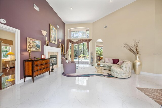 sitting room featuring a towering ceiling and a tiled fireplace