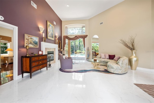 living room with a tile fireplace, a high ceiling, and plenty of natural light