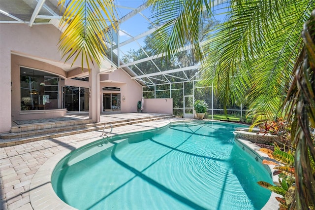 view of pool with glass enclosure and a patio