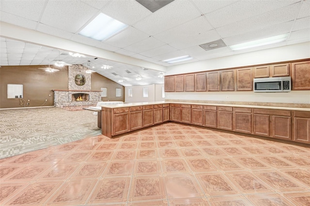 kitchen with kitchen peninsula, vaulted ceiling, and a fireplace