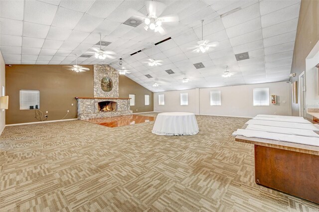 interior space with a stone fireplace, light carpet, and a drop ceiling