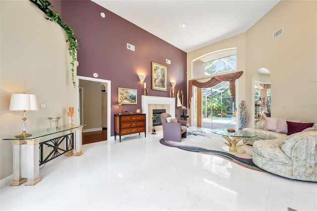 living room featuring a tiled fireplace and a high ceiling