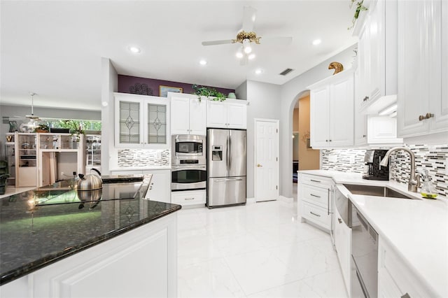 kitchen with decorative backsplash, stainless steel appliances, ceiling fan, sink, and white cabinetry