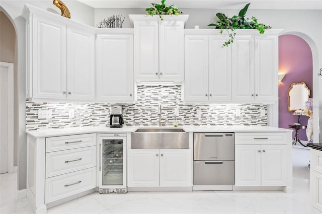 kitchen with white cabinetry, sink, beverage cooler, stainless steel dishwasher, and backsplash