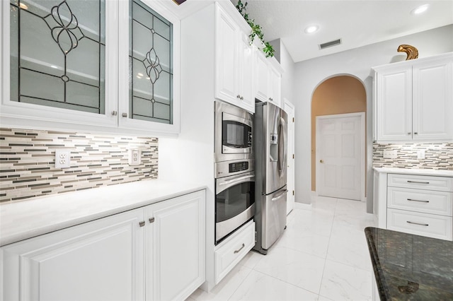 kitchen with decorative backsplash, white cabinets, and stainless steel appliances