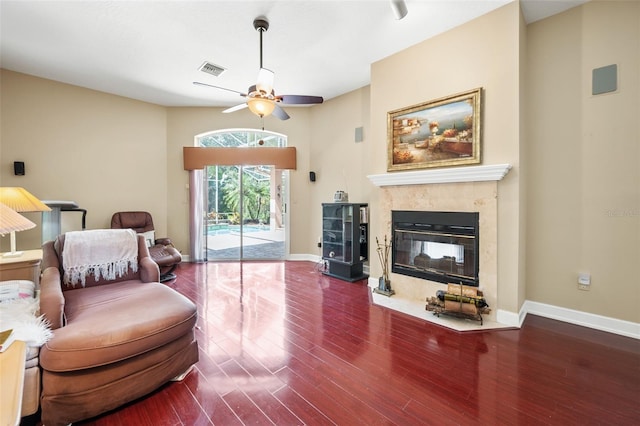 living room with a high end fireplace, wood-type flooring, and ceiling fan