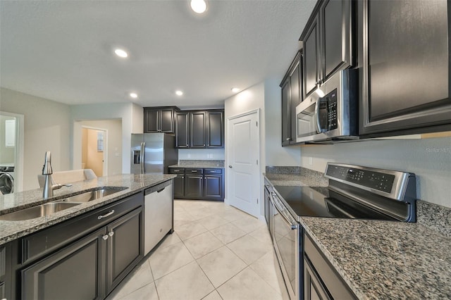 kitchen with sink, light tile patterned floors, dark stone counters, and appliances with stainless steel finishes