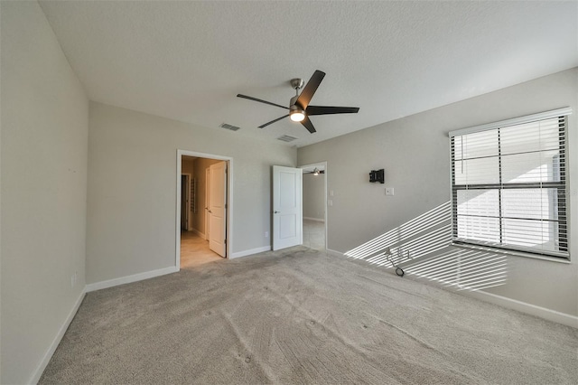 carpeted spare room with a textured ceiling and ceiling fan