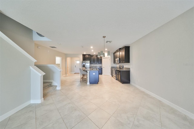 16850 Whisper Elm St, Wimauma, FL 33598 - kitchen featuring stainless steel appliances, a kitchen island with sink, light tile patterned flooring, baseboards, and open floor plan