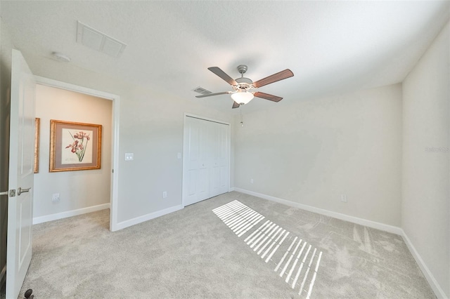 unfurnished bedroom with light colored carpet, ceiling fan, and a closet