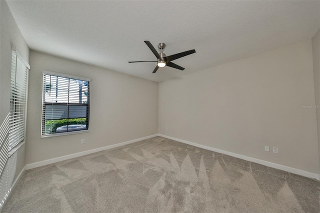 spare room with carpet floors, ceiling fan, baseboards, and a textured ceiling