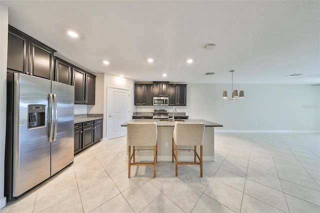 kitchen featuring light tile patterned flooring, a kitchen island with sink, recessed lighting, a sink, and appliances with stainless steel finishes