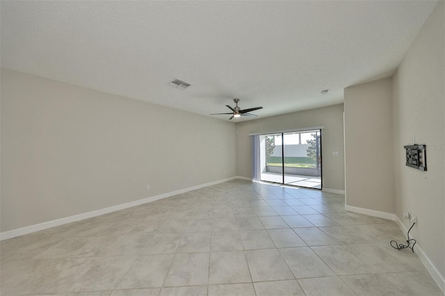 empty room with baseboards, visible vents, ceiling fan, and light tile patterned flooring