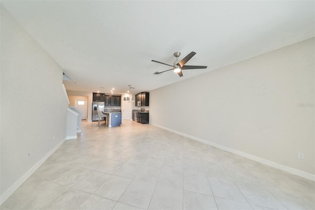 unfurnished living room featuring ceiling fan and baseboards