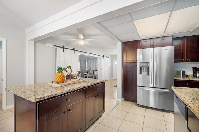 kitchen featuring a drop ceiling, a barn door, stainless steel appliances, and light tile patterned floors