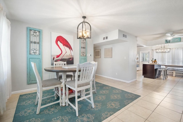 tiled dining space featuring ceiling fan with notable chandelier