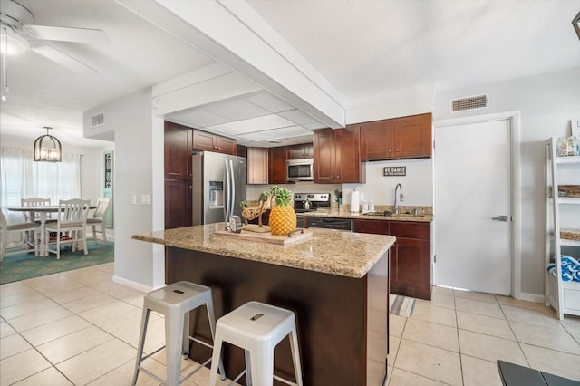 kitchen with a center island, appliances with stainless steel finishes, and a kitchen bar