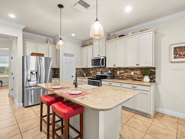 kitchen with pendant lighting, an island with sink, white cabinets, stainless steel appliances, and crown molding