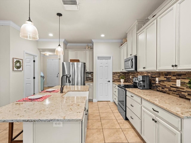 kitchen with appliances with stainless steel finishes, hanging light fixtures, an island with sink, and white cabinets