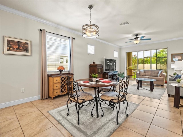 tiled dining area with ceiling fan with notable chandelier, ornamental molding, and a healthy amount of sunlight