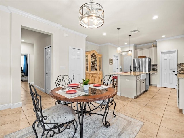 tiled dining area featuring ornamental molding, an inviting chandelier, and sink