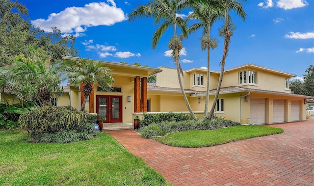 view of front facade with a front yard, french doors, and a garage