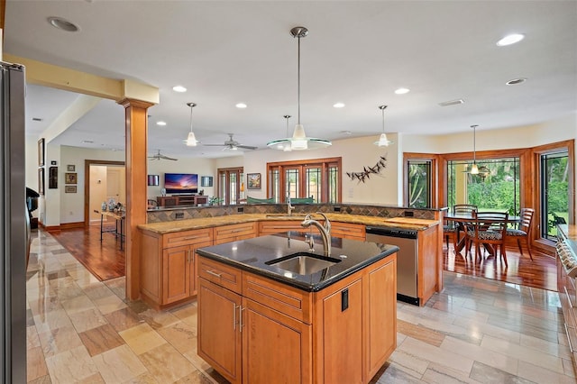 kitchen featuring an island with sink, pendant lighting, ceiling fan, stainless steel dishwasher, and sink