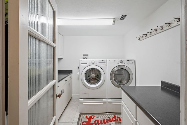 laundry area featuring cabinets, light tile patterned floors, and washing machine and clothes dryer