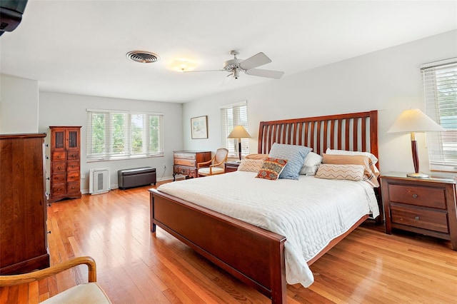 bedroom with ceiling fan, light hardwood / wood-style floors, and multiple windows