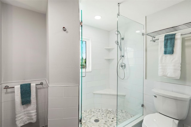 bathroom with tile walls, toilet, and an enclosed shower