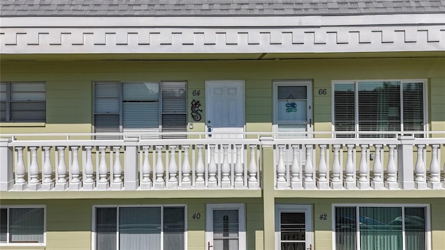 exterior space featuring a shingled roof and a balcony