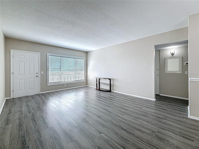 unfurnished living room featuring dark wood-style flooring, a textured ceiling, and baseboards