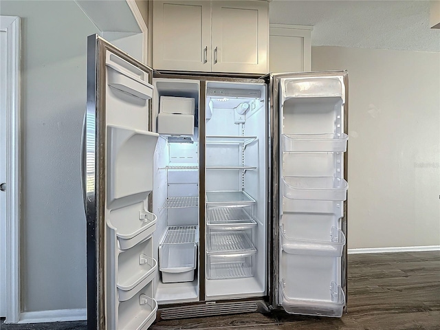 details featuring dark wood-type flooring, fridge, and baseboards