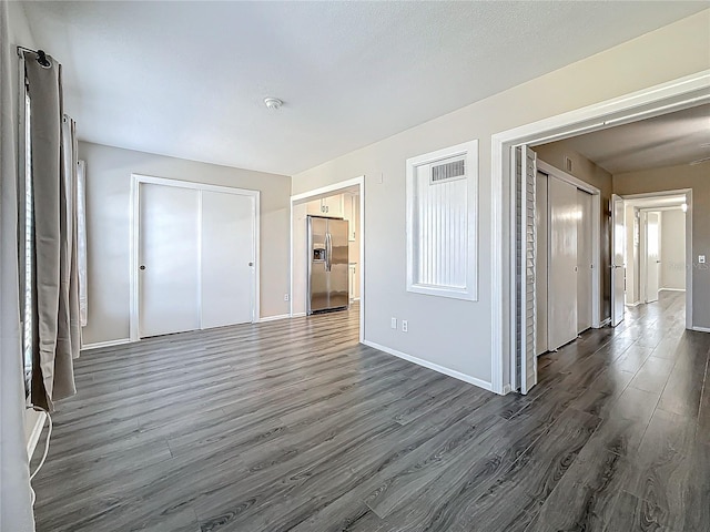 unfurnished room with visible vents, baseboards, and dark wood finished floors