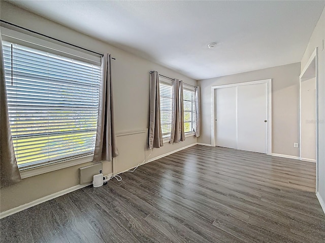 interior space featuring dark wood-type flooring, a closet, and baseboards