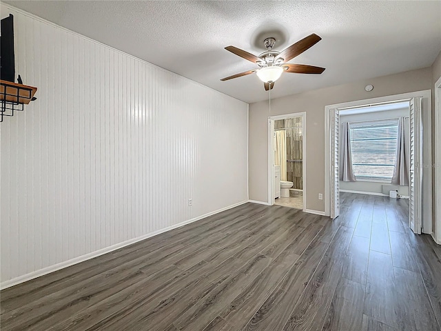 interior space featuring dark wood-style floors, baseboards, a ceiling fan, and a textured ceiling