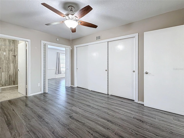 unfurnished bedroom featuring dark wood-type flooring, visible vents, and a textured ceiling