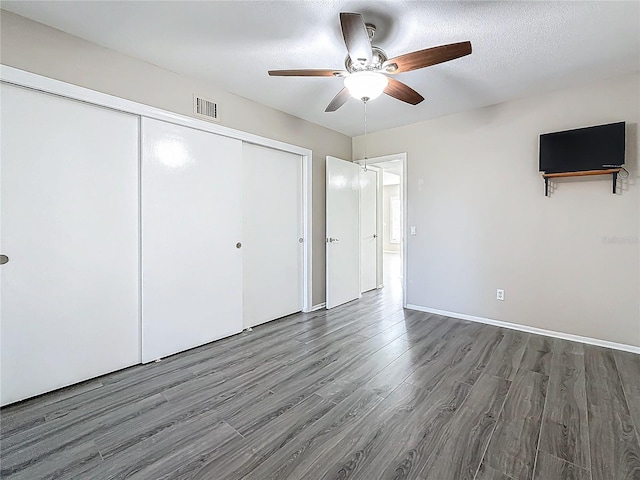 unfurnished bedroom with visible vents, a ceiling fan, dark wood-style floors, a textured ceiling, and a closet