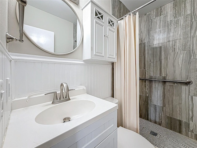 full bathroom with toilet, a shower stall, vanity, and wainscoting