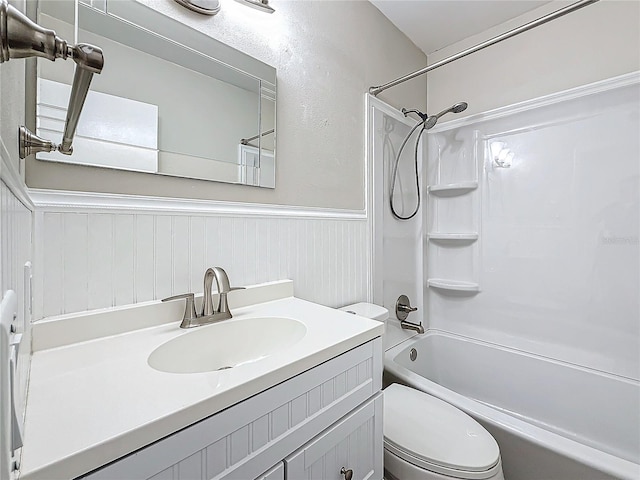 full bathroom featuring a wainscoted wall, toilet, vanity, and shower / tub combination