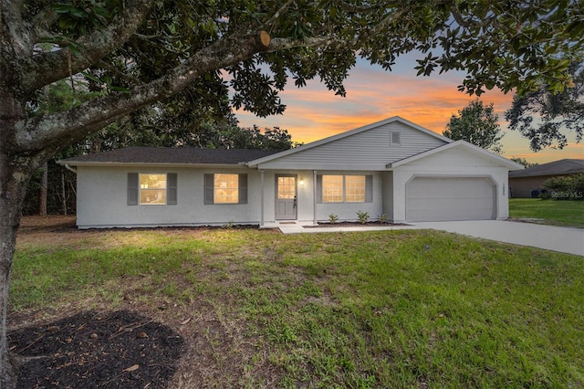 single story home featuring a lawn and a garage