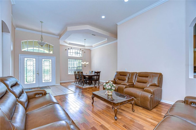 living room with ornamental molding, light wood-type flooring, a notable chandelier, and french doors