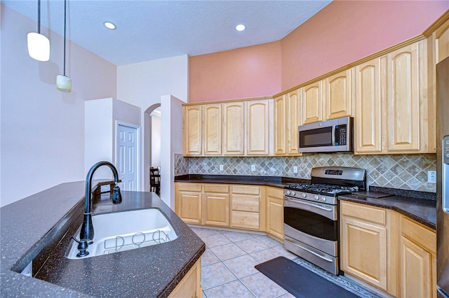 kitchen with light brown cabinets, hanging light fixtures, light tile patterned floors, sink, and appliances with stainless steel finishes