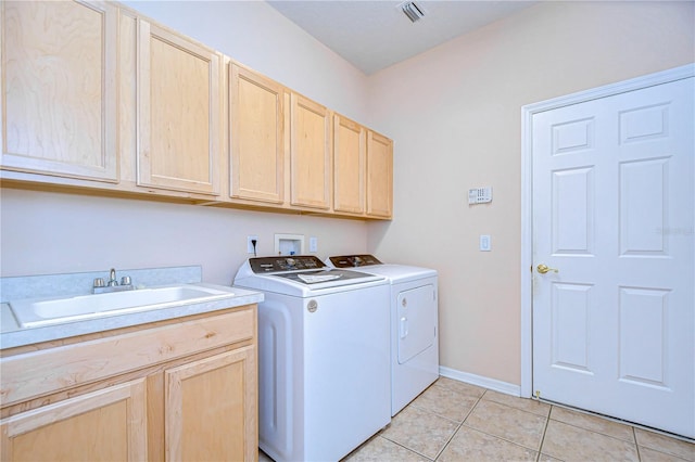 clothes washing area with cabinets, light tile patterned flooring, sink, and washing machine and clothes dryer